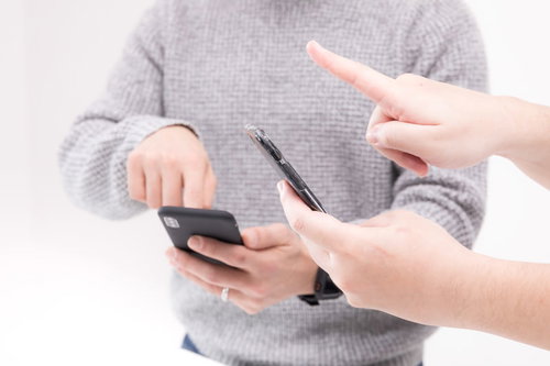 スマホを使って仲間とゲームをするふたり