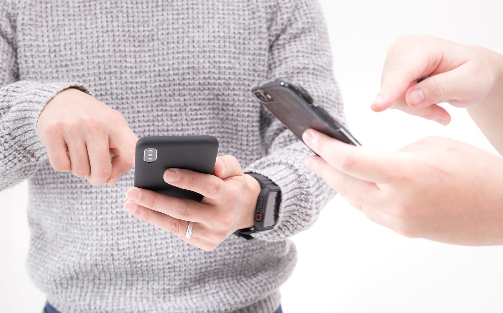 グレーのニットを着た人がスマートフォンでデータ共有している手元