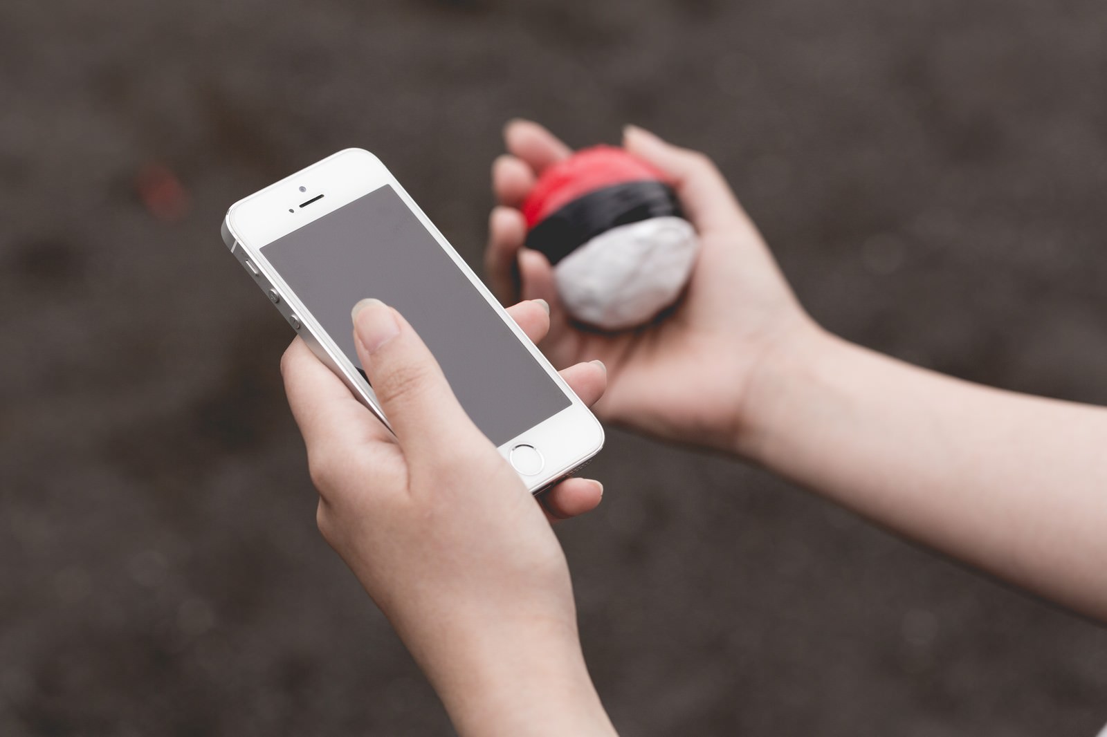 スマホとモンスターボールを持つ子どもの手元
