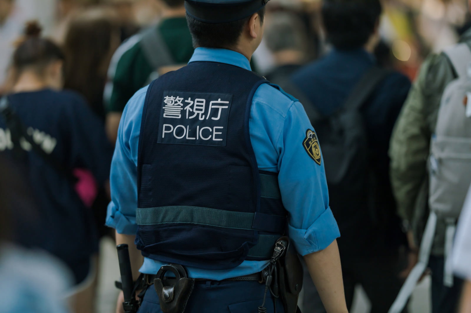 青い制服を着た警察官が街中でパトロールしている後ろ姿