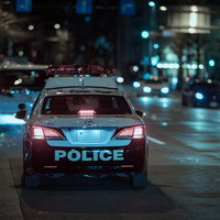深夜にパトロールするパトカーの後姿、青いライトが点灯の写真