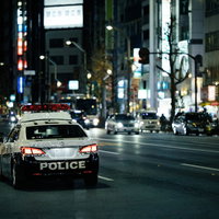 夜の繁華街を巡回するパトカーの写真