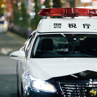 夜のネオンと停車中の警察車両、赤色灯点灯の写真