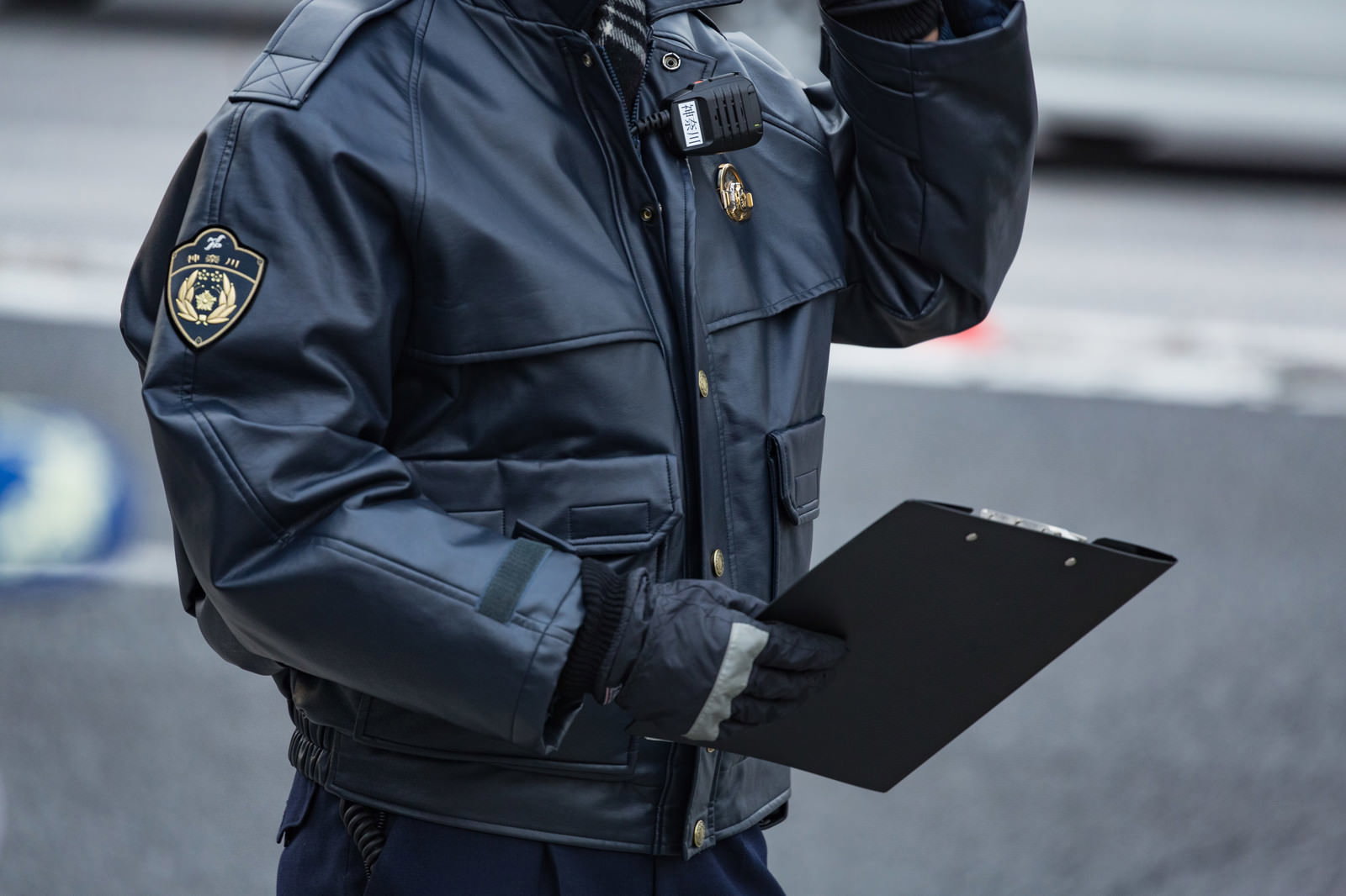 紺色の制服を着た警察官が手帳を持ち職務質問を行っている様子