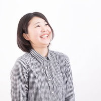 チェックシャツを着て上を見上げて堪えられず思わず笑う女性の写真