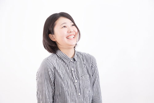 チェックシャツを着て上を見上げて堪えられず思わず笑う女性