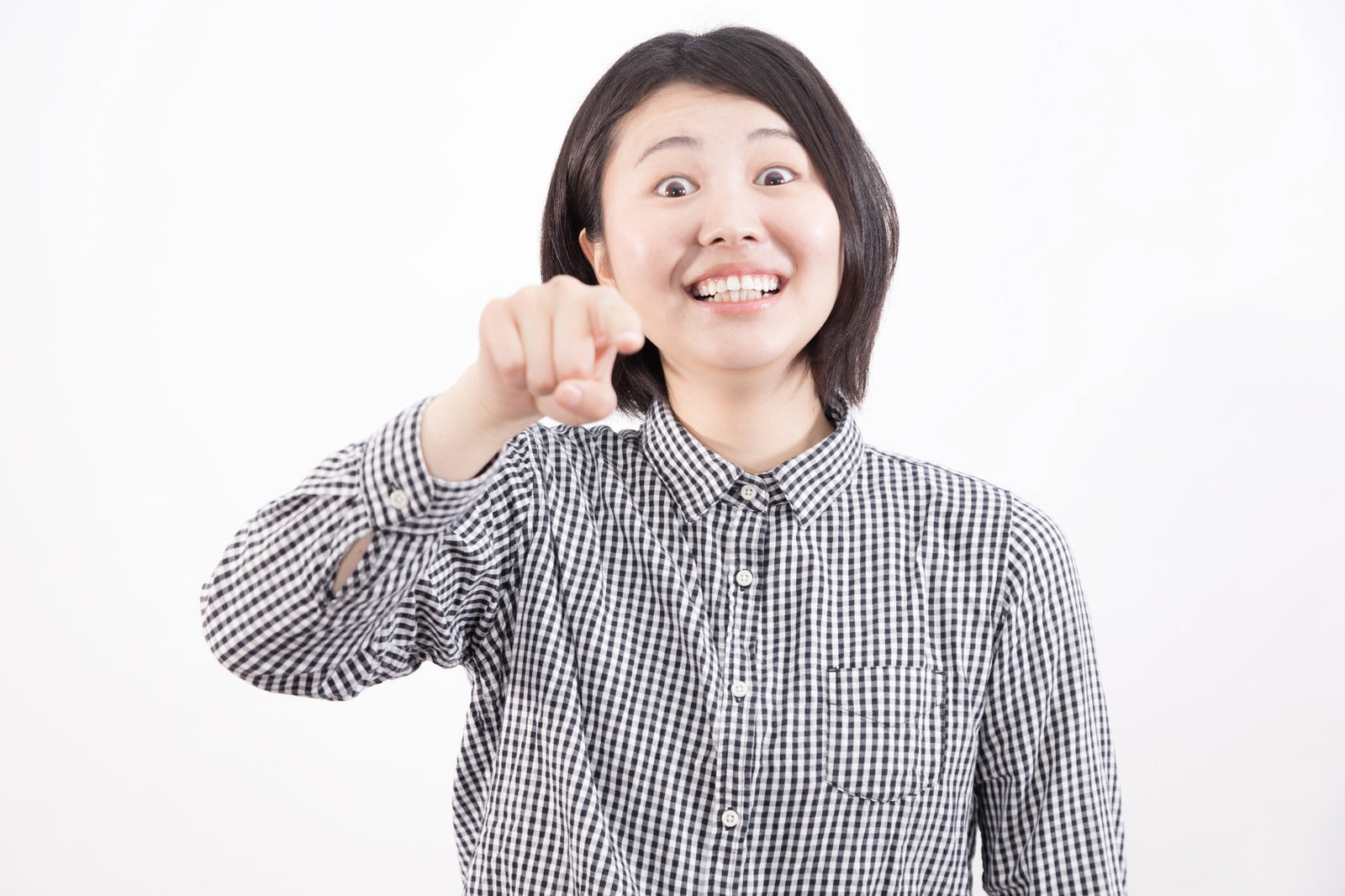 チェックシャツを着た女性が右手で指差しをしながら笑顔を見せている［モデル：佐竹PP］