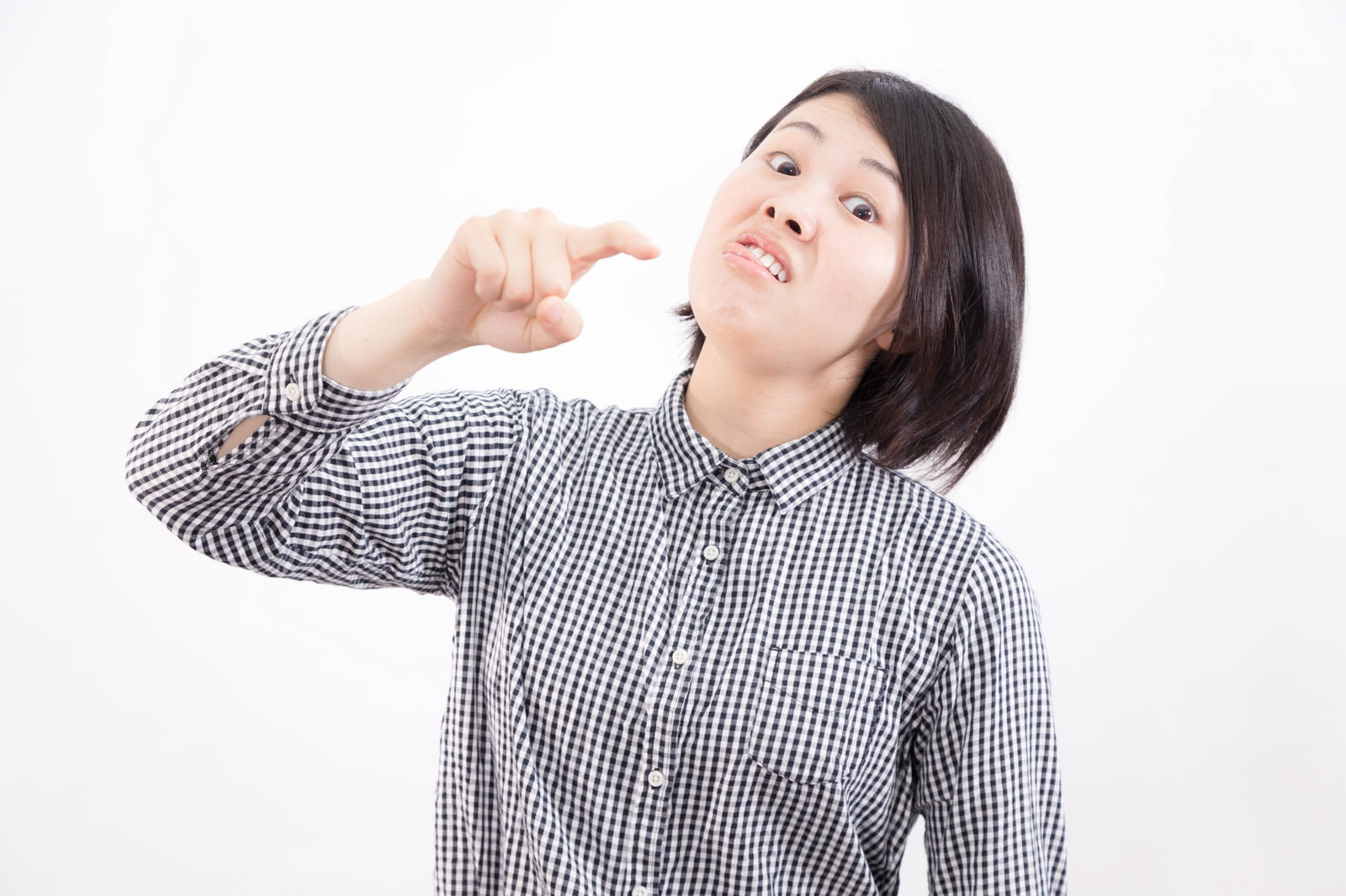 チェック柄シャツを着た女性が右手で指をさしながら怒りの表情を見せている［モデル：佐竹PP］