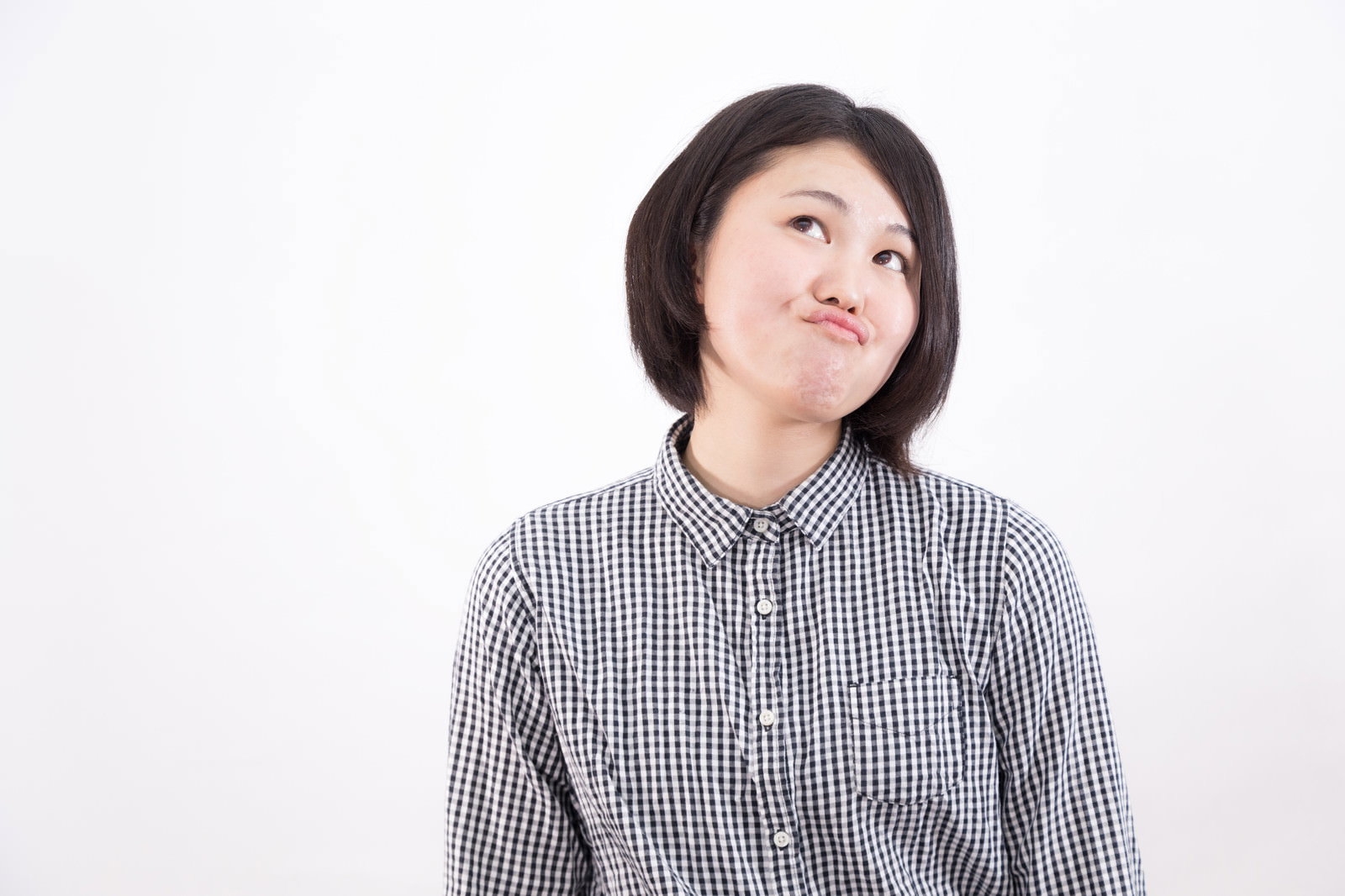 チェックシャツを着た女性が上を見上げて困惑したような表情をしている［モデル：佐竹PP］