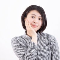 歯痛ポーズで盛れると聞いて、片手を頬に当てる女性の写真