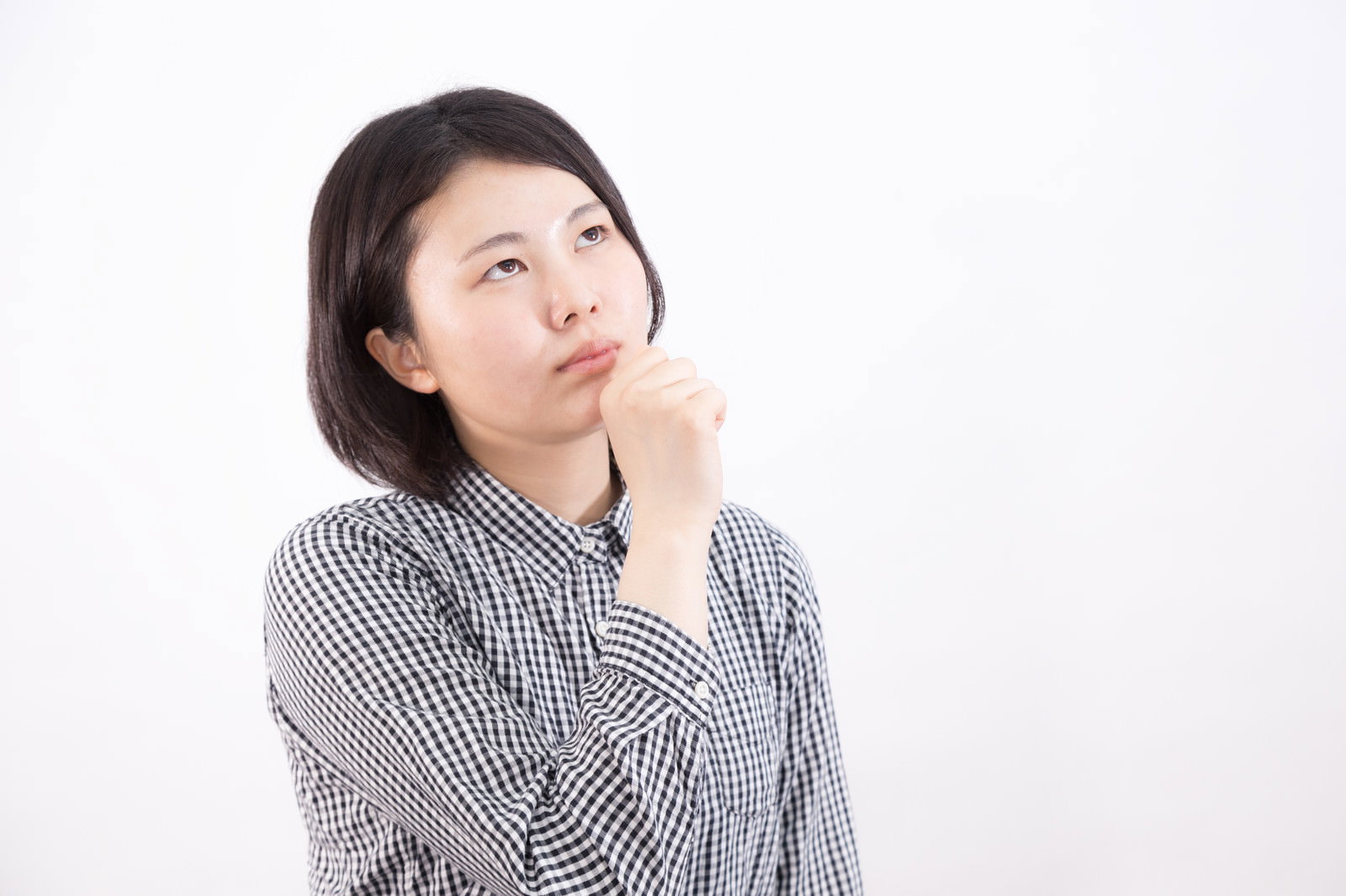 グレーのストライプシャツを着た女性が顎に手を当てて上を見上げている［モデル：佐竹PP］