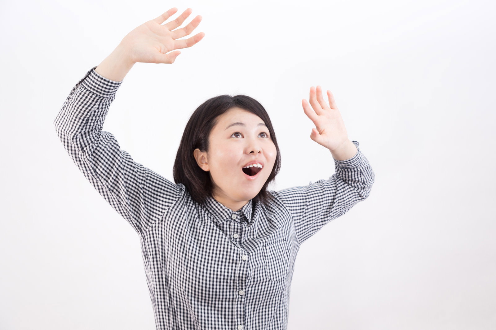 ストライプシャツを着た女性が両手を上げて驚いた表情をしている［モデル：佐竹PP］