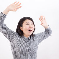 ストライプシャツを着て両手を上げて驚く女性の写真