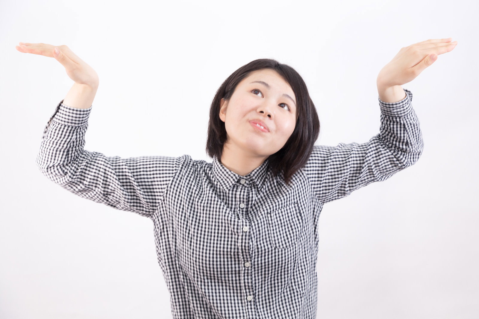 グレーのストライプシャツを着た女性が両手を上げて驚いた表情を見せている［モデル：佐竹PP］