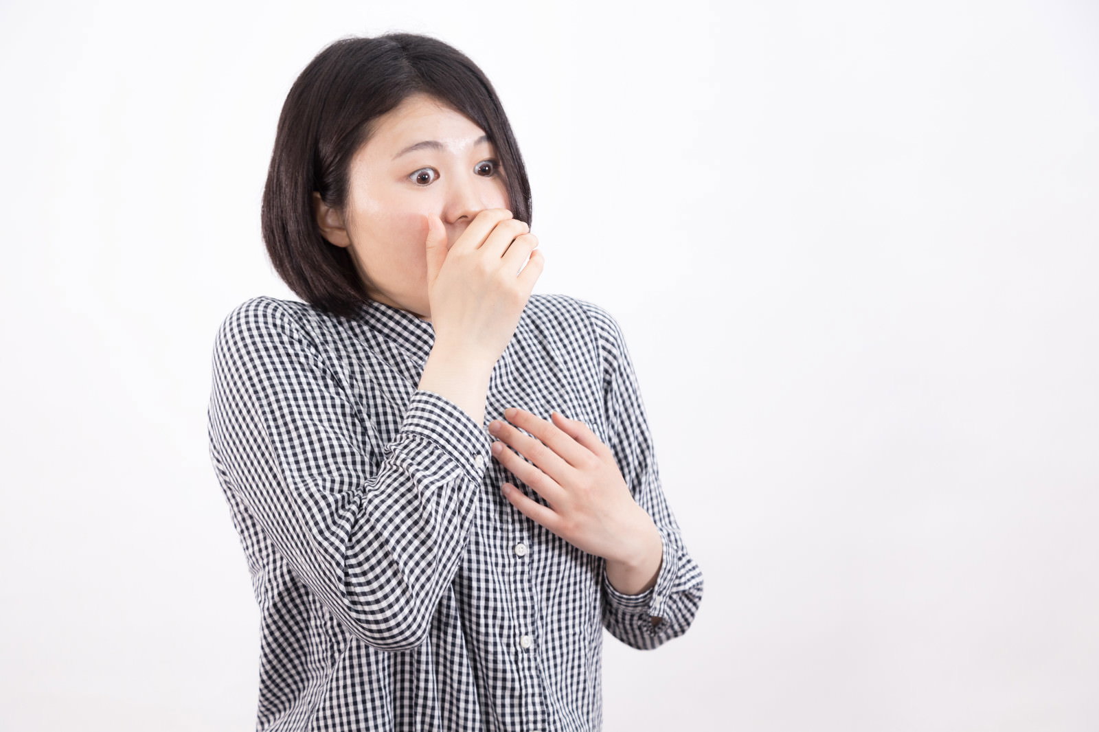 目を丸くして口元に手を当てて驚く表情の女性［モデル：佐竹PP］