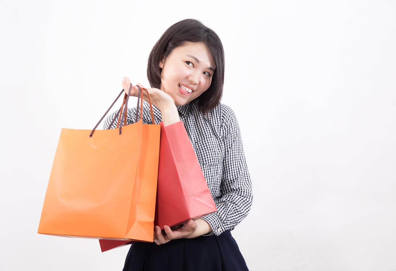 オレンジとピンクの買い物袋を持ちガッツポーズをする女性［モデル：佐竹PP］