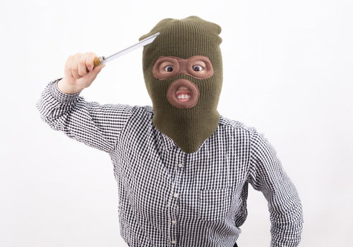 刃物を持った覆面姿の強盗女性が犯行を示唆するポーズ