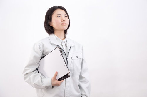 書類ファイルを持つグレーの作業着姿の女性作業員