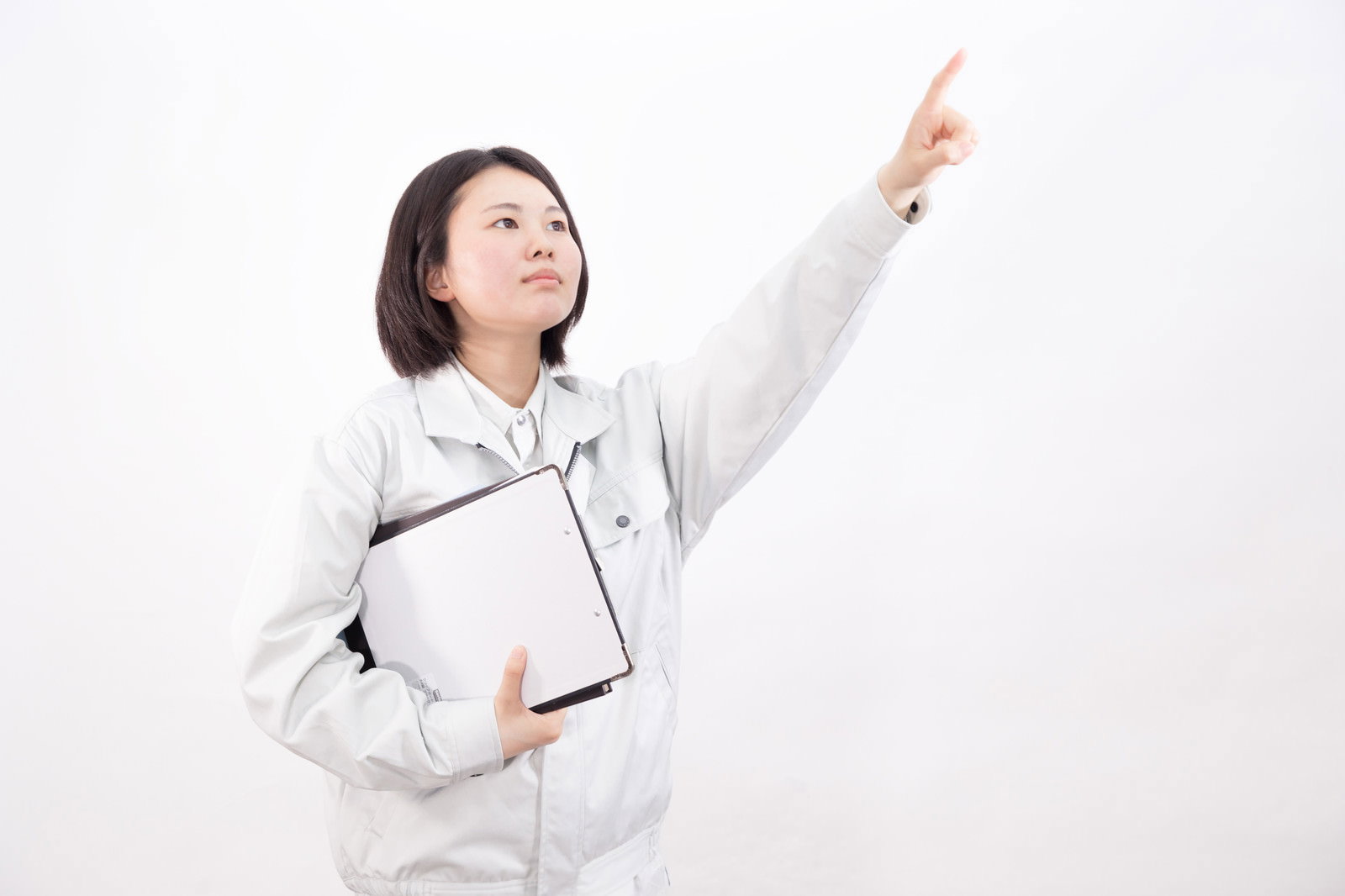 白いヘルメットとグレーの作業着を着た女性が人差し指を上に向けて目標を掲げるポーズ［モデル：佐竹PP］