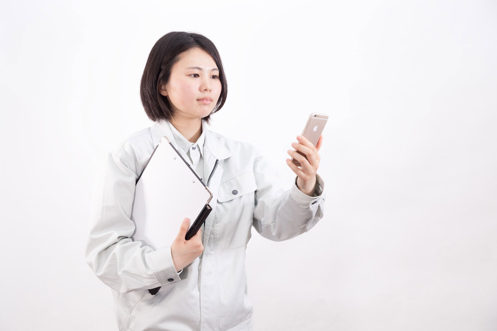 白い作業着を着た女性がスマートフォンを操作している［モデル：佐竹PP］