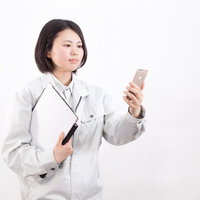 スマホで日報を確認する現場女子の業務管理の写真