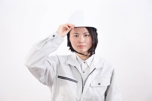頭部を守るヘルメットをかぶった作業着の女性