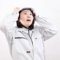 ヘルメットをしっかり押さえる女性作業員の安全対策の写真