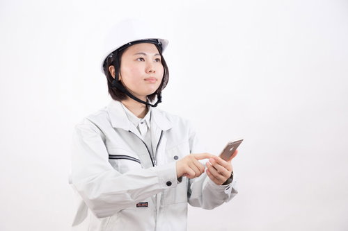 スマートフォンでリモート操作する現場作業員の女性