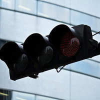 ビルの前で点灯するLEDの赤信号の写真