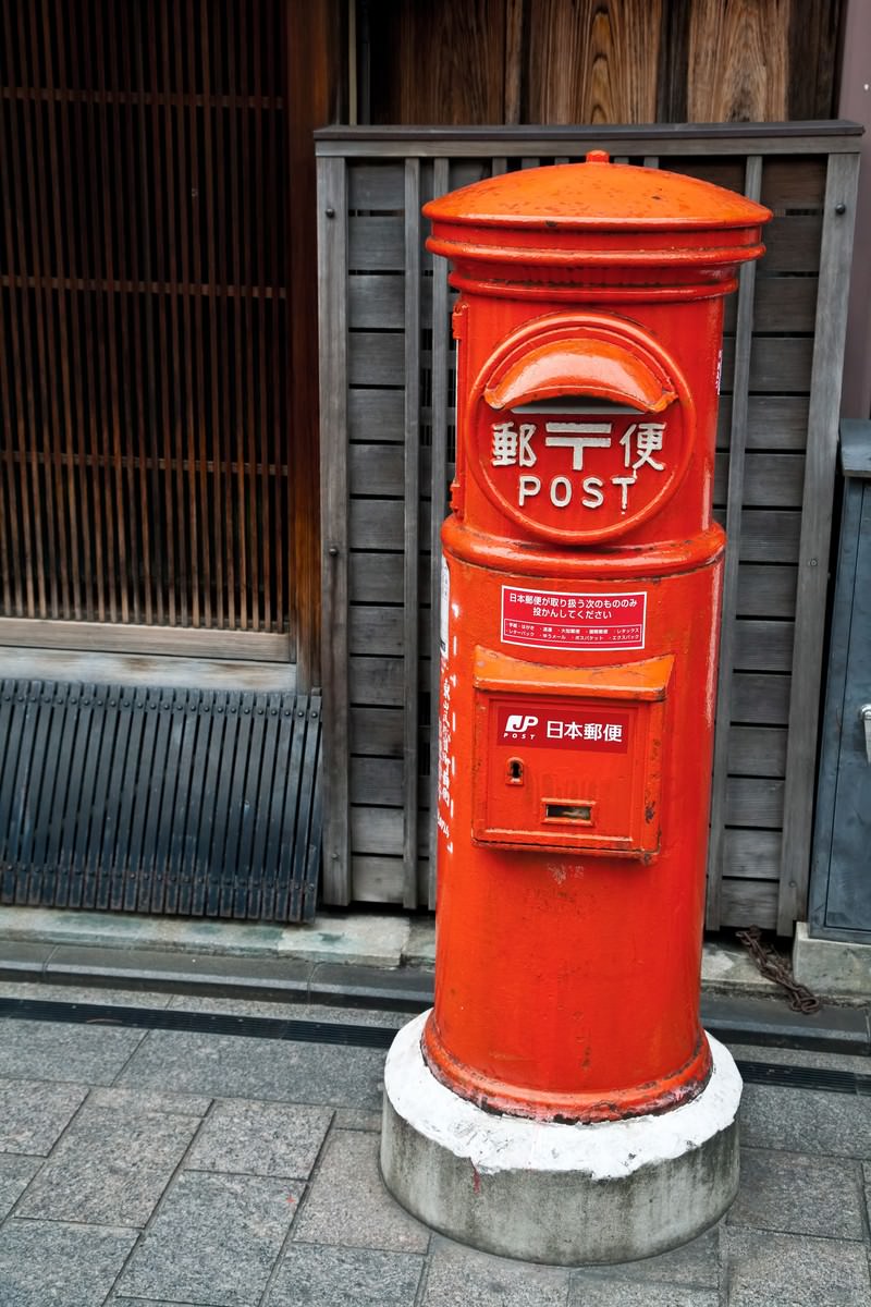 石畳の通りに立つ赤い郵便ポスト