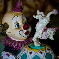 紫の帽子をかぶり白い犬を持つ古びたピエロの人形の写真