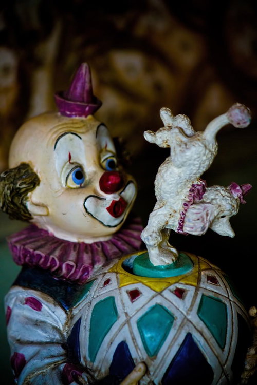 紫の帽子をかぶり白い犬を持つ古びたピエロの人形