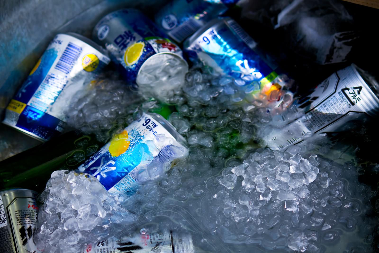 暗い室内で氷に埋もれて冷えるビールの缶