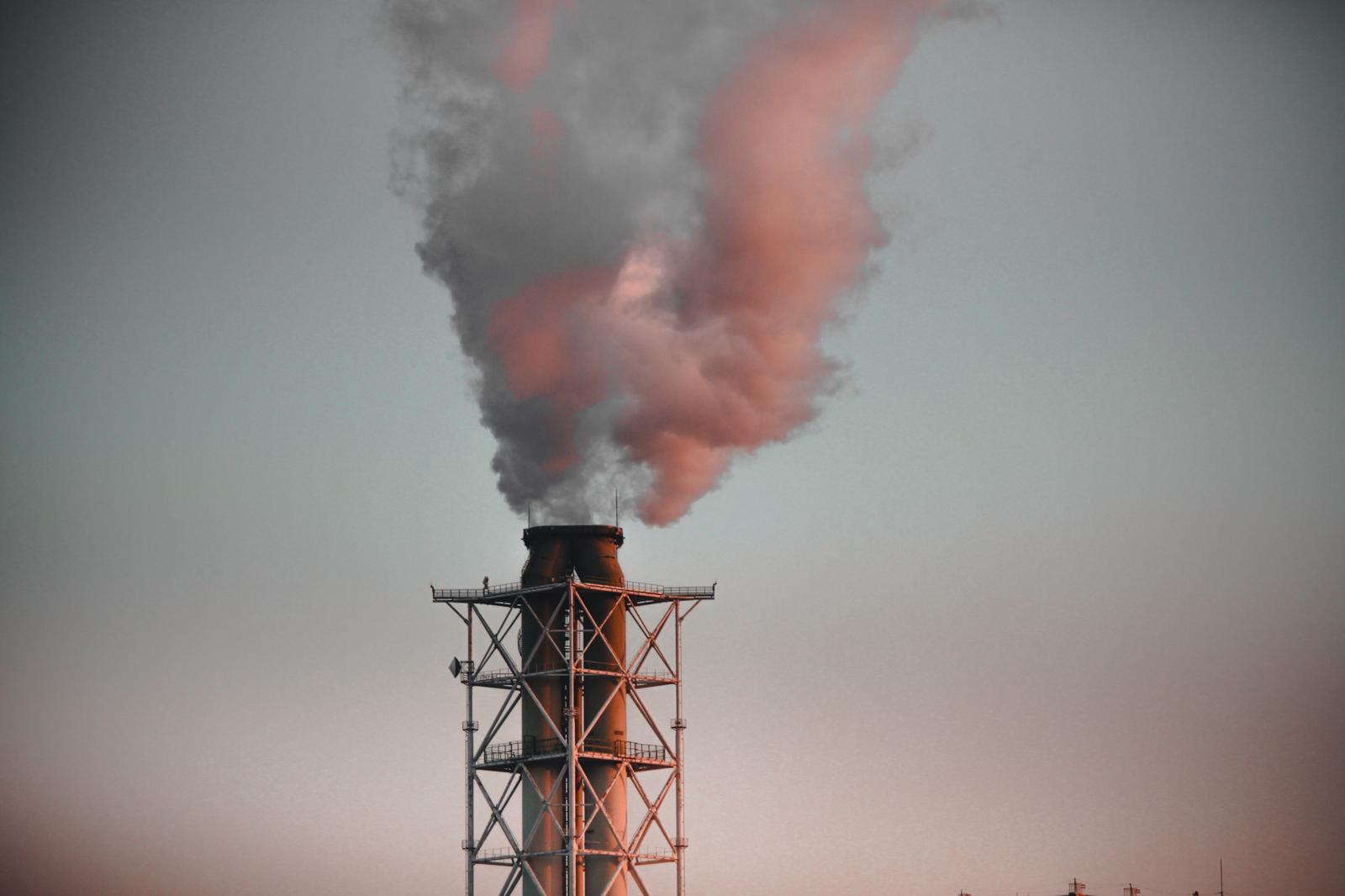 赤い煙突から立ち上る白く濃い排煙と大気汚染