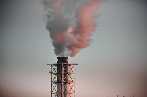赤く染まる排煙をあげる工場の煙突と大気汚染