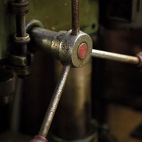 赤いボタンが付いた古いボール盤の緑のハンドルの写真