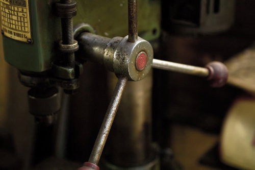 赤いボタンが付いた古いボール盤の緑のハンドル