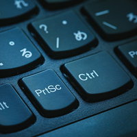 キーボードのプリントスクリーンボタンを青い光で照らした操作キーの写真