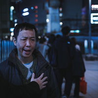 夜の繁華街で制止される憤慨男性の写真