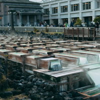 湯畑から立ち上がる白い湯気と温泉の源泉施設の写真