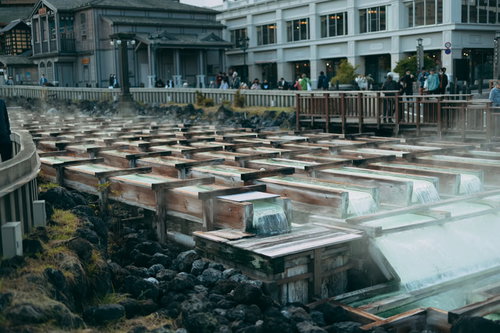 湯畑から立ち上がる白い湯気と温泉の源泉施設