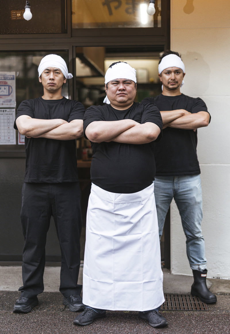 白いコック帽とエプロンを着た男性店員が厨房前で腕組みしてドヤ顔のポーズ［モデル：段田隼人 大川竜弥 Max_Ezaki］