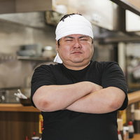 ドヤ顔で腕組みをするラーメン屋の店主の厨房での一枚の写真