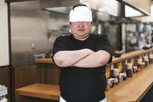 つけめん屋の店主が厨房で腕組みしてドヤ顔