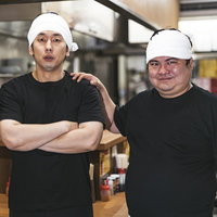 期待の新人を紹介するラーメン店主と弟子の厨房での一枚の写真
