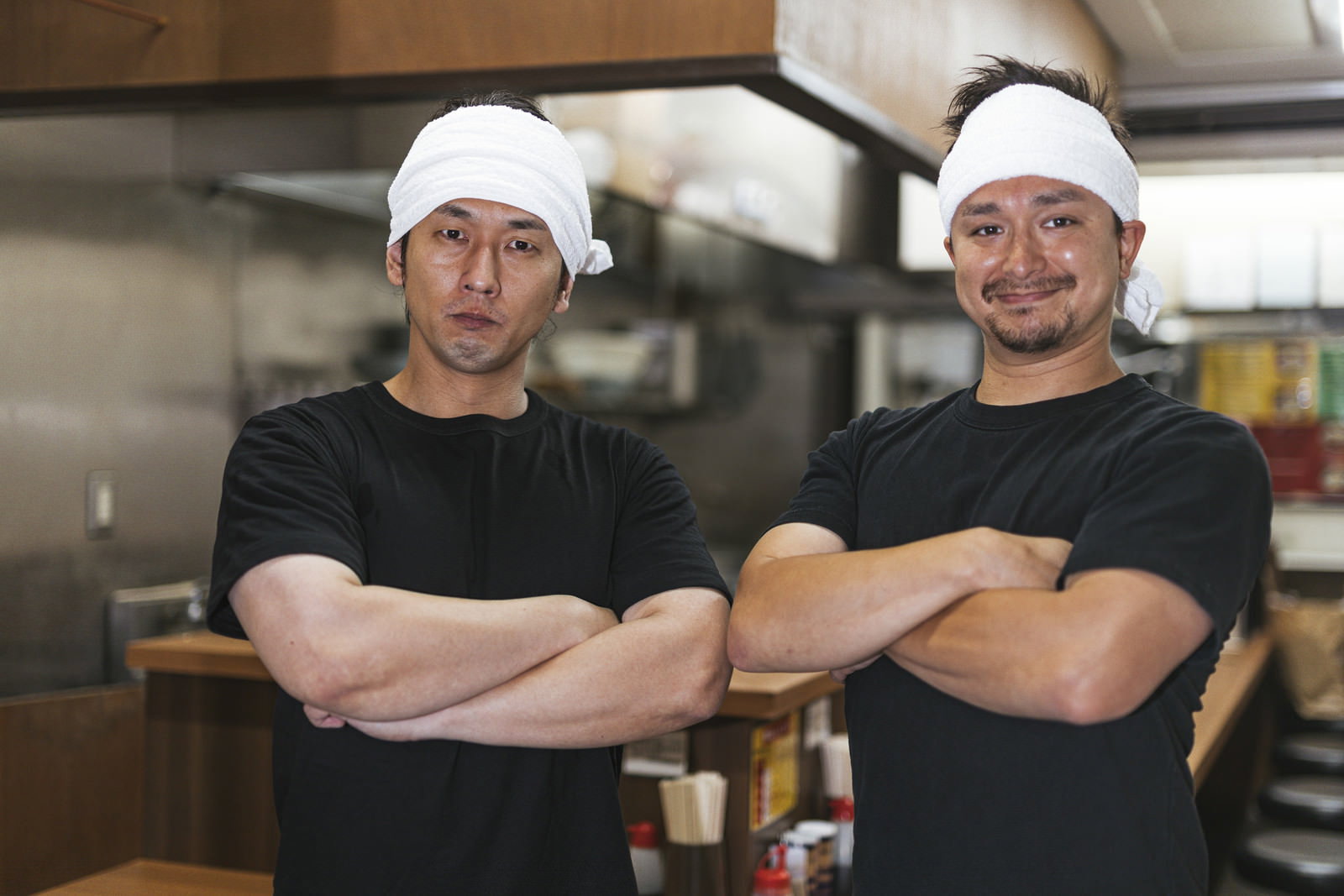 厨房で腕組みをしてドヤ顔を決める白帽子の男性ラーメン店員［モデル：大川竜弥 Max_Ezaki］