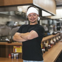 ラーメン屋の厨房で腕組みするドイツ人ハーフ店員の写真