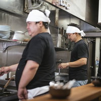 ラーメン屋の厨房で働く3人の男性店員による調理作業の風景の写真