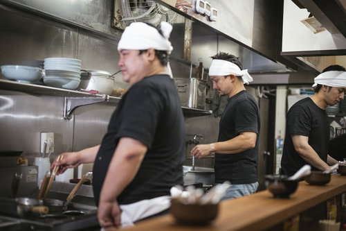 ラーメン屋の厨房で働く3人の男性店員による調理作業の風景