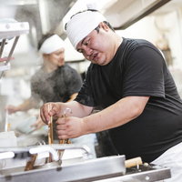 麺の硬さを見極めるラーメン職人の厨房での仕事の写真